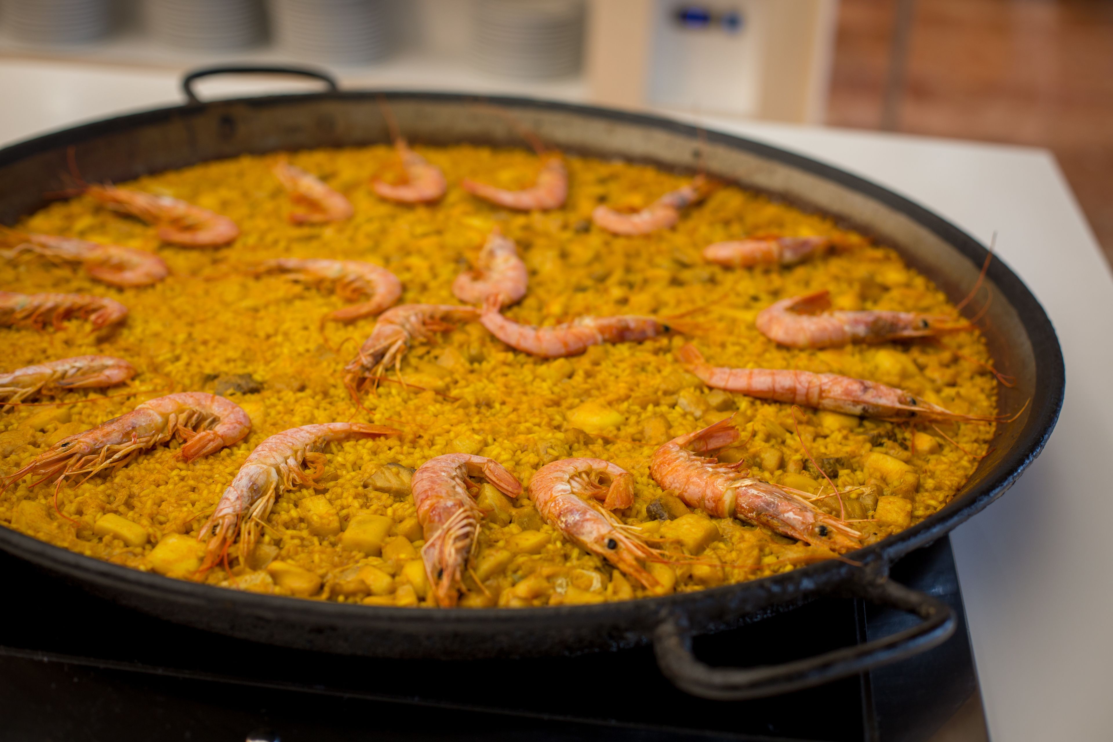 Une grande poêle remplie de riz jaune et de plusieurs crevettes.