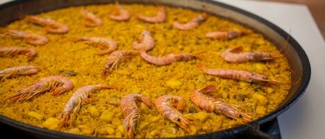 Une grande poêle remplie de riz jaune et de plusieurs crevettes.