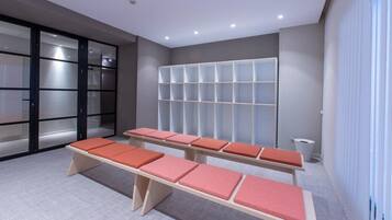 Un área de espera moderna con un mostrador de recepción, una zona de estar con bancos acolchados y un mueble de almacenamiento empotrado.