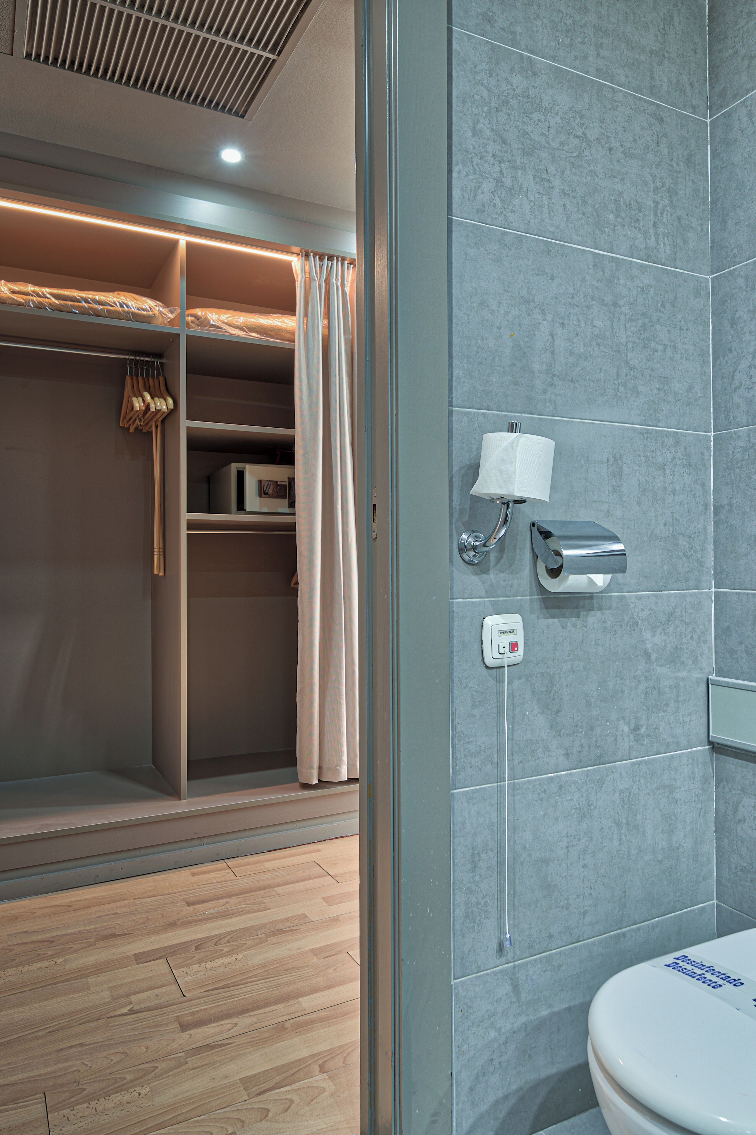 A modern bathroom with a toilet, a towel dispenser, and a shower area.