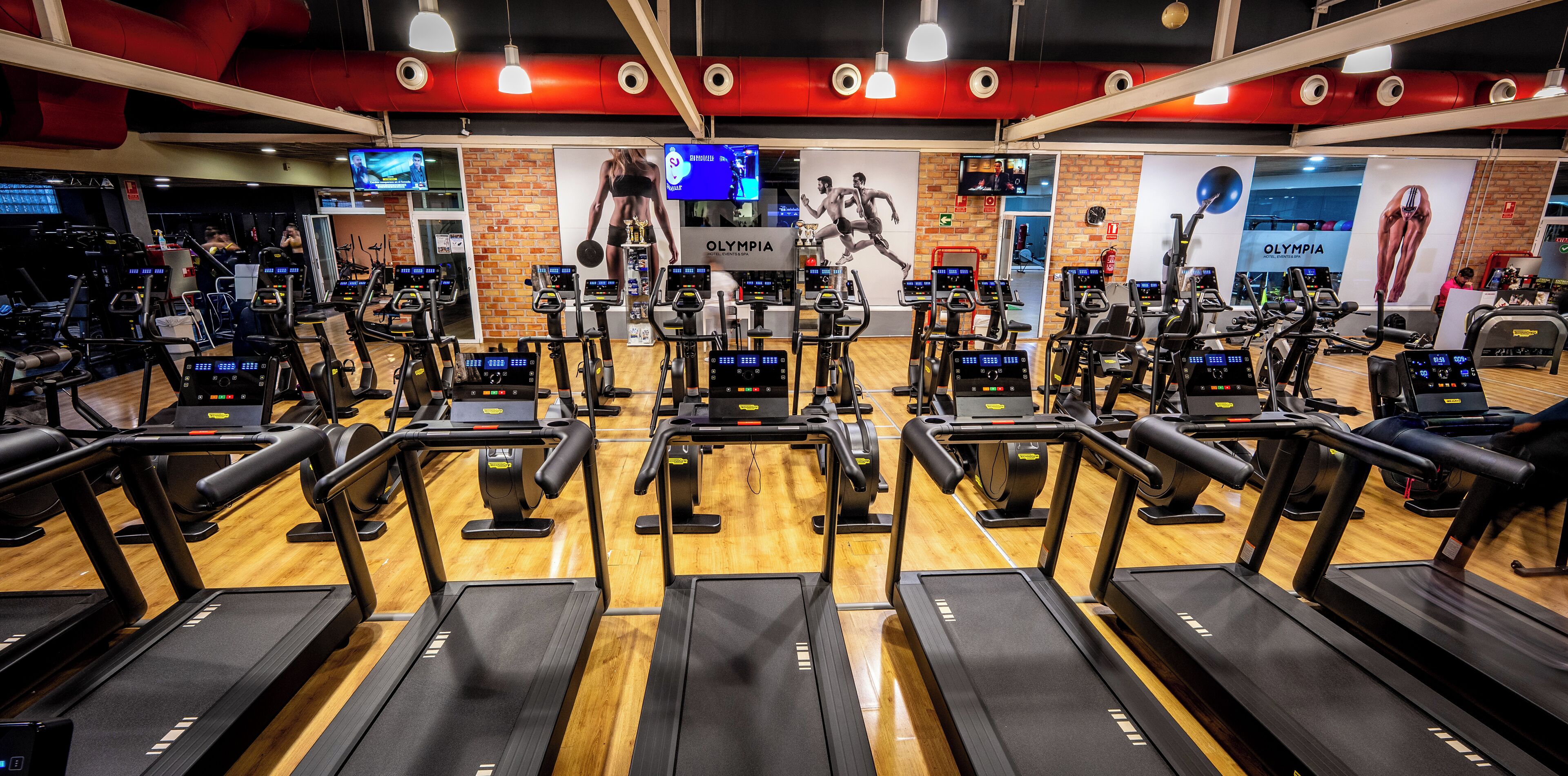 A gym with multiple treadmills, stationary bikes, and elliptical machines.