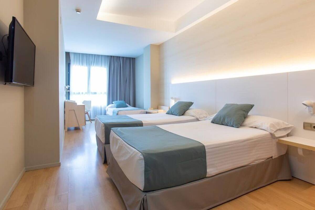 Une chambre d’hôtel avec deux lits, une télévision et un bureau.