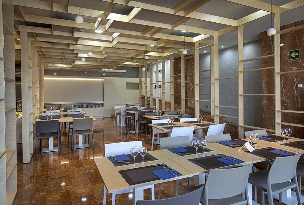 Una sala de conferencias moderna con mesas dispuestas para reuniones, equipada con tarjetas de identificación y vasos de agua.