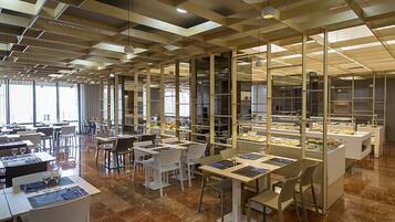 A modern restaurant with a geometric ceiling design, marble flooring, and a variety of seating arrangements.