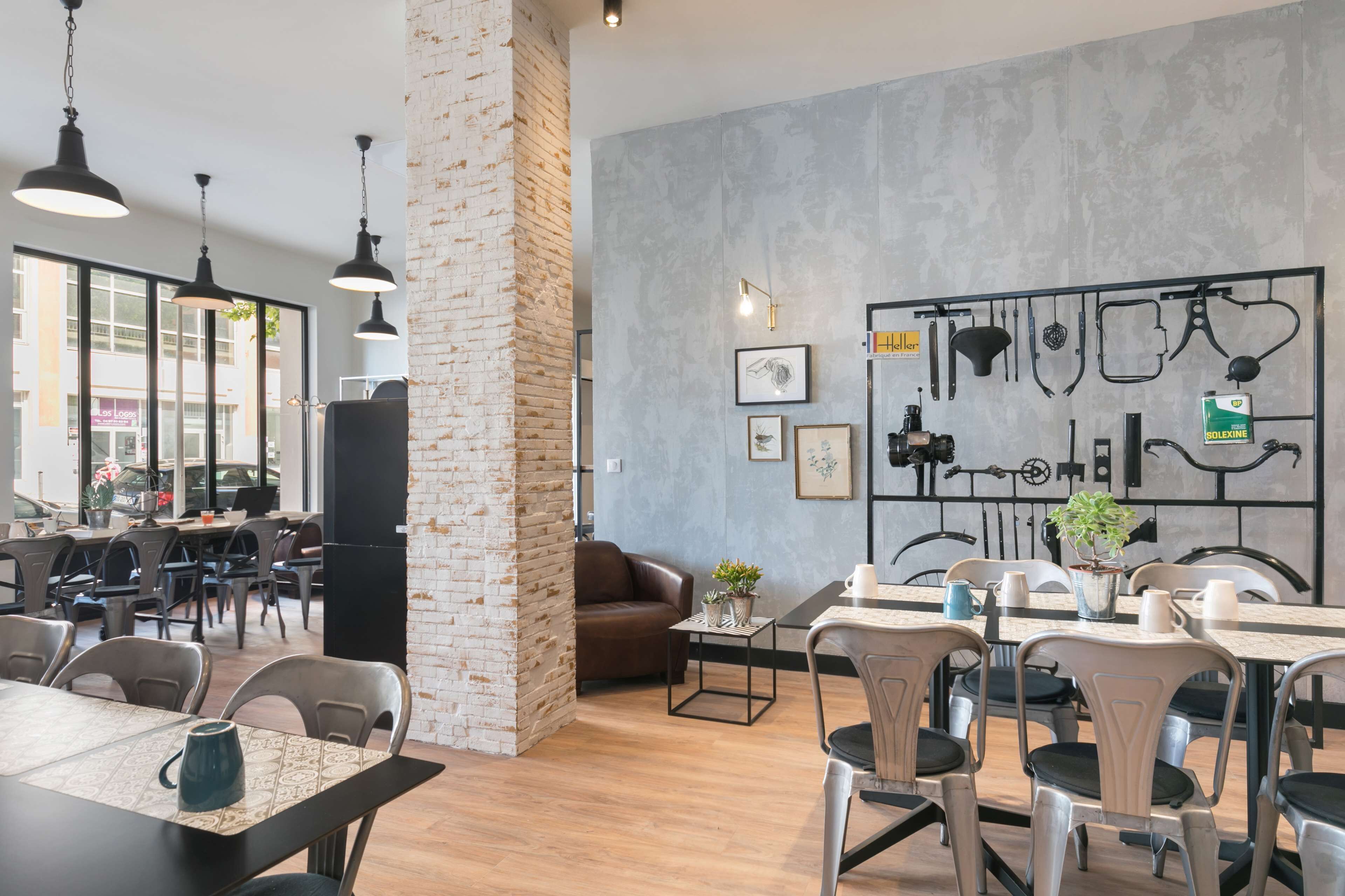 Un café moderno con paredes de ladrillo visto, iluminación colgante y una exhibición de componentes de bicicleta en la pared.