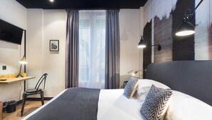 A modern hotel room with a large bed, a desk, and a TV mounted on the wall. - Hôtel So'Co by HappyCulture (Nice)