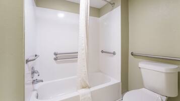 A bathroom with a bathtub, toilet, and shower curtain.