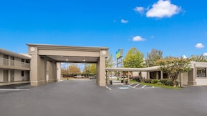 A hotel entrance with a covered walkway, parking lot, and a sign indicating a nearby business. - SureStay Hotel by Best Western Columbus Downtown (Columbus)