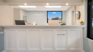 A reception desk with a sign reading "SureStay Hotel by Best Western," a computer, and a small plant. - SureStay Hotel by Best Western Columbus Downtown (Columbus)
