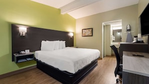 A hotel room with a bed, bedside table, lamp, and a desk with a chair. - SureStay Hotel by Best Western Columbus Downtown (Columbus)
