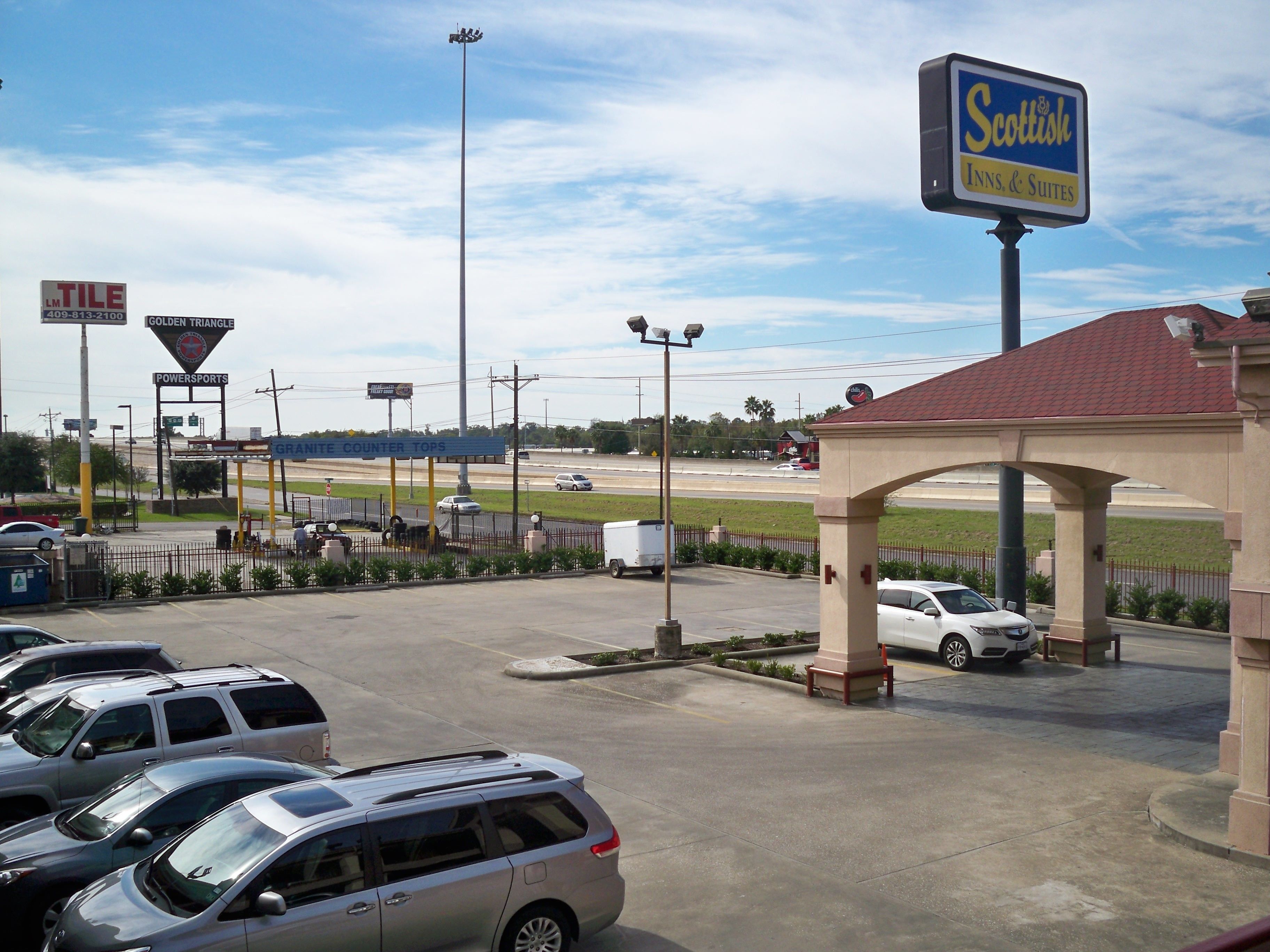 A parking lot with several cars, a sign for "Scottish Inns & Suites," and a "Golden Triangle" sign.