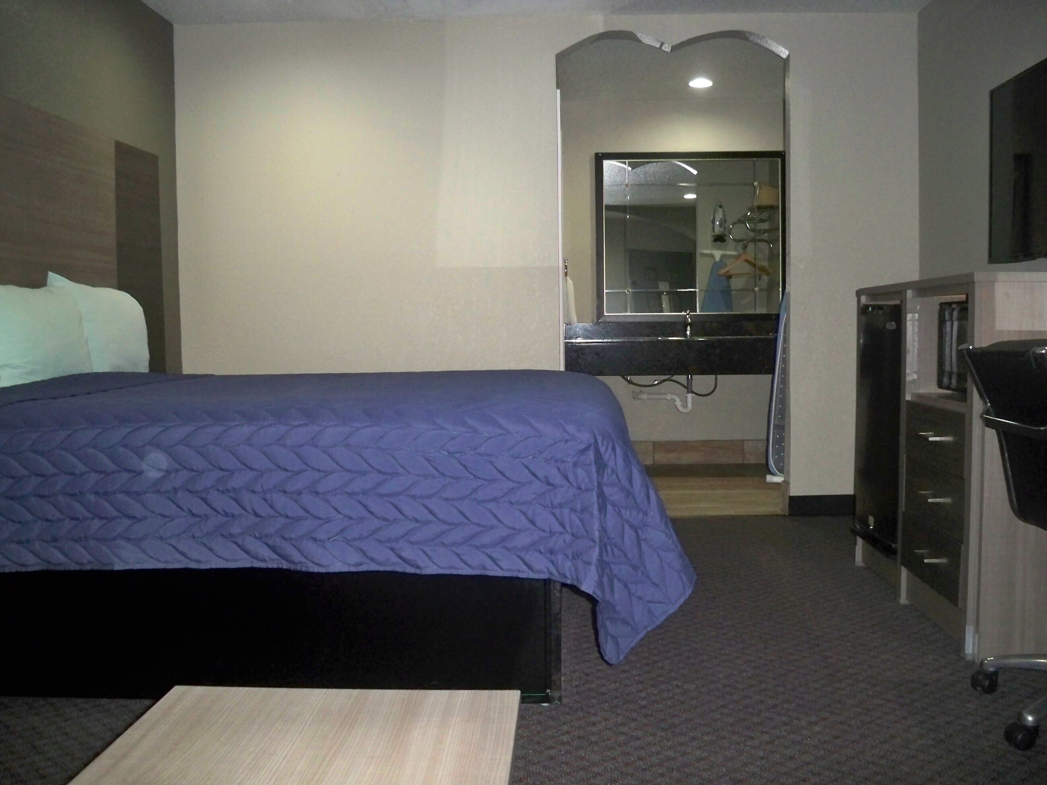 Ein Hotelzimmer mit Bett, Schreibtisch, Spiegel und Kleiderschrank.