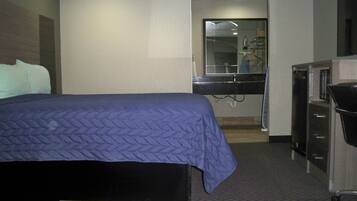 Ein Hotelzimmer mit Bett, Schreibtisch, Spiegel und Kleiderschrank.