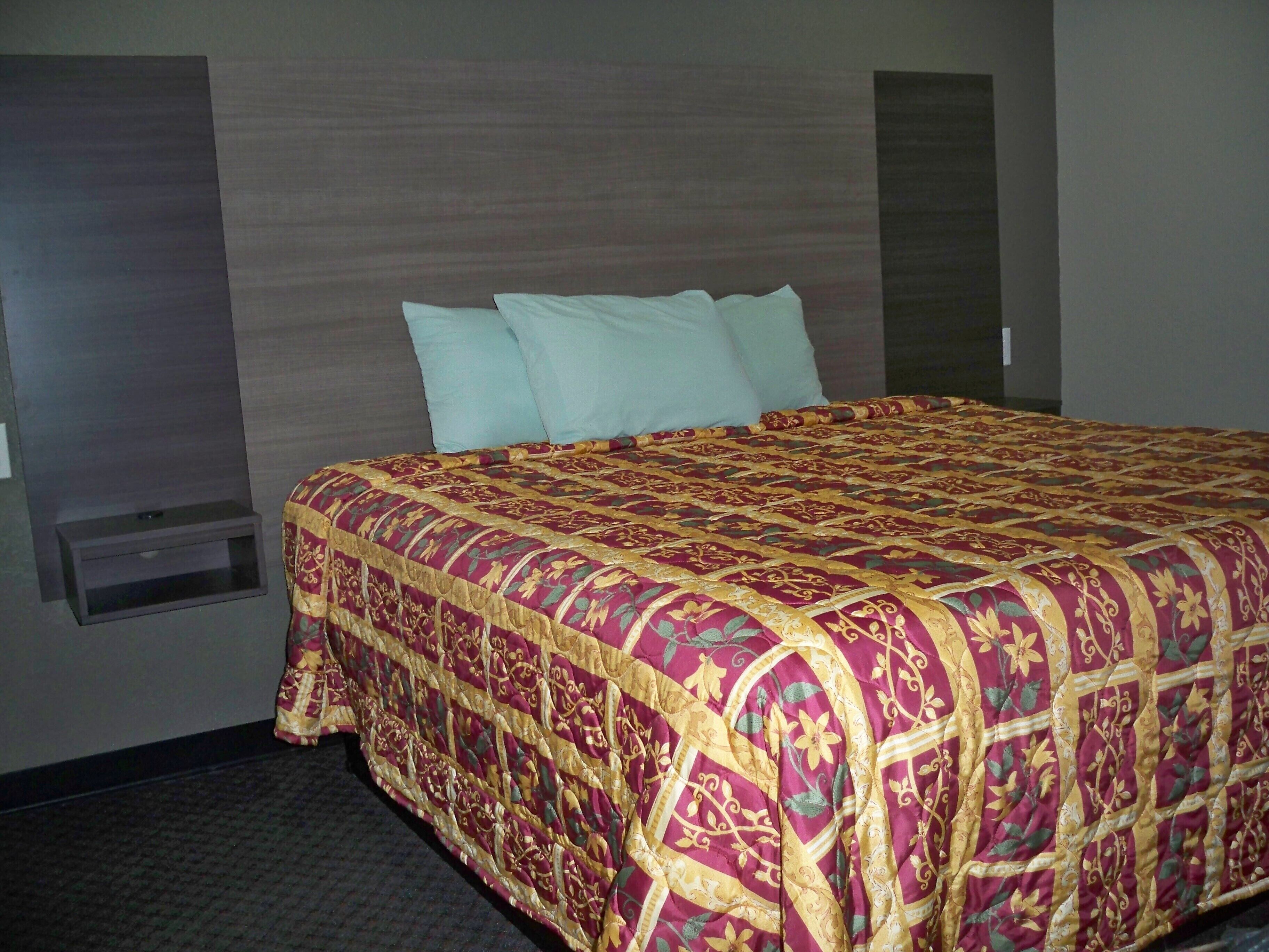Una habitación de hotel con una cama grande, un cabecero y una mesita de noche pequeña.