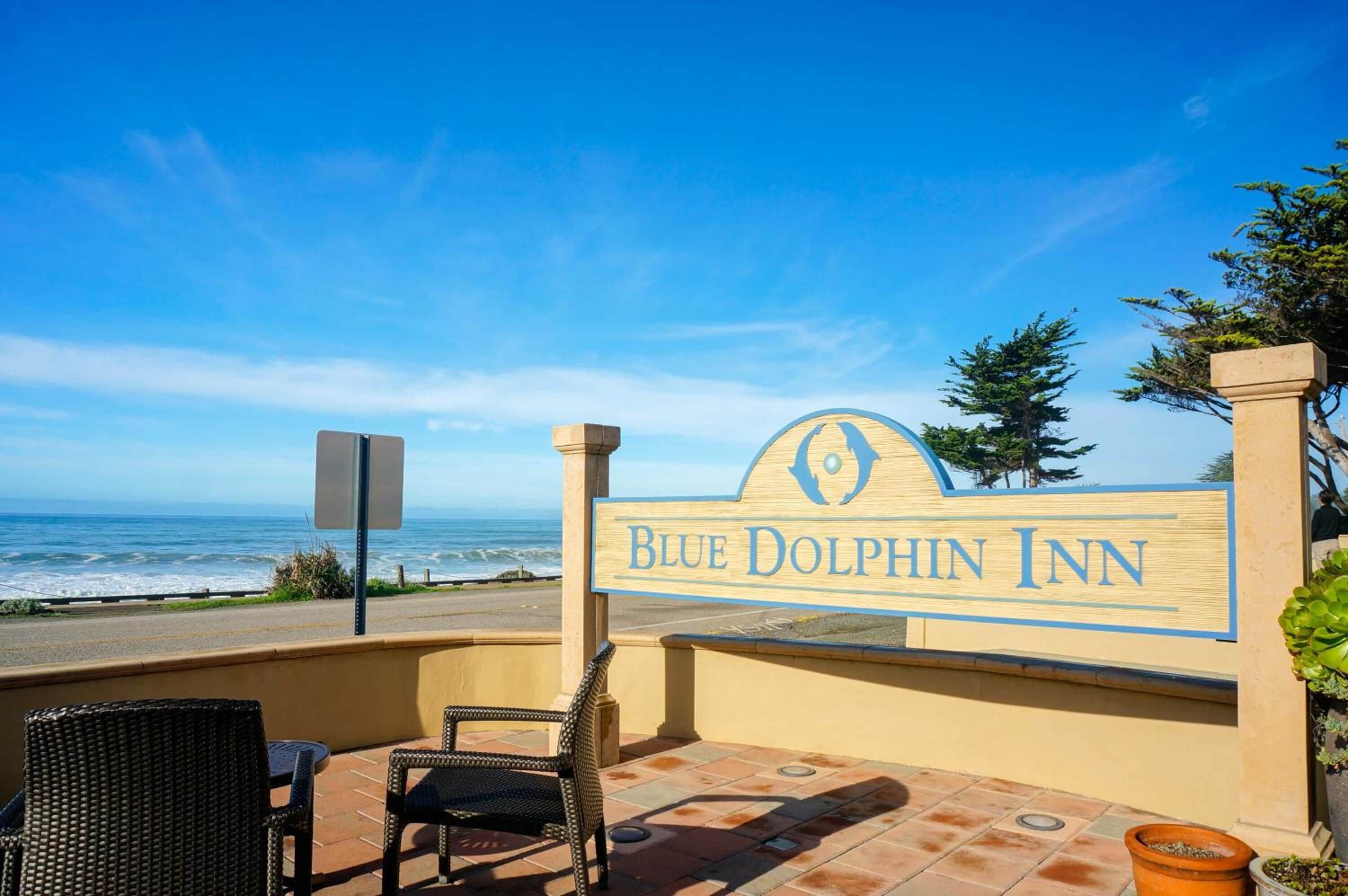 A Blue Dolphin Inn sign with a view of the ocean.