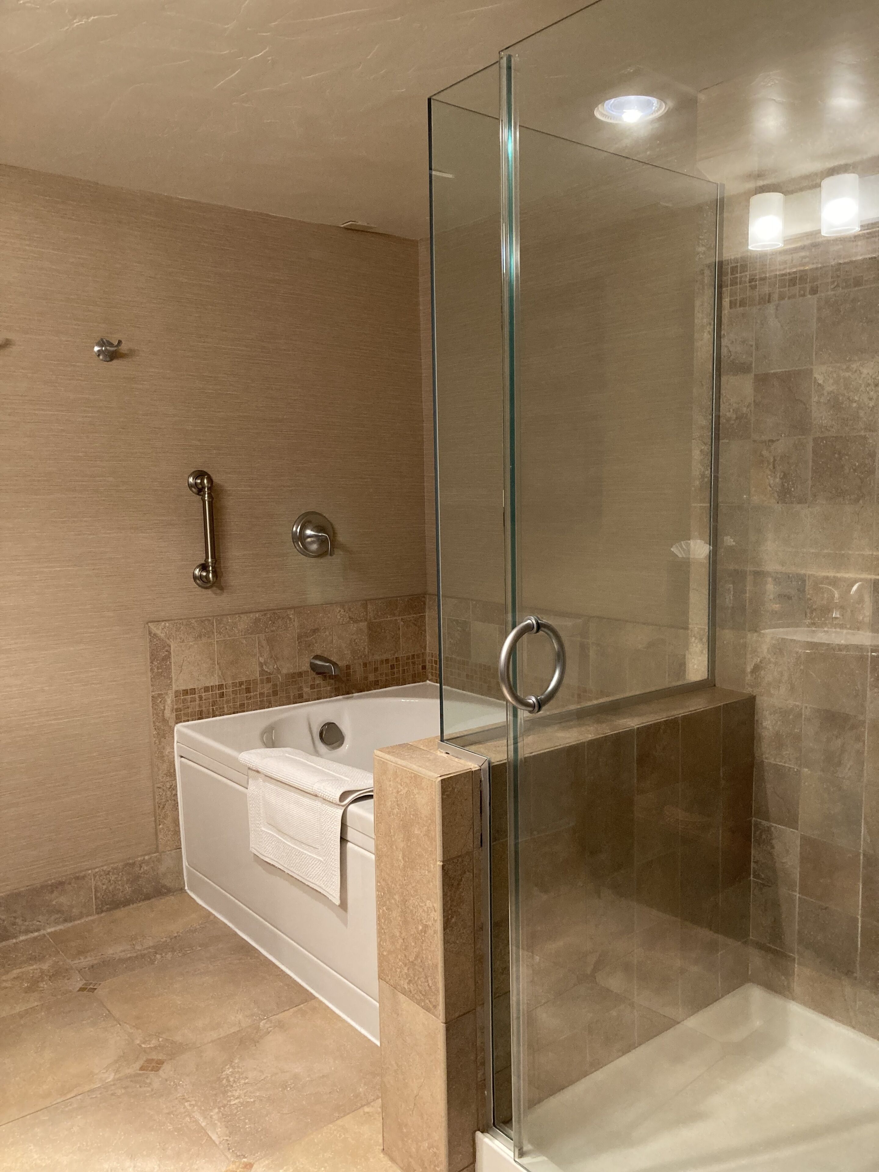 Een moderne badkamer met een douchecabine van glas, een vrijstaand bad en een wastafel met een handdoek.
