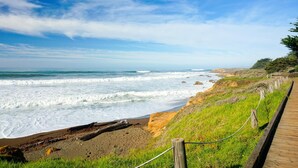 A coastal walkway with a wooden boardwalk, grassy areas, and rocky cliffs overlooking the ocean. - Blue Dolphin Inn (Cambria)