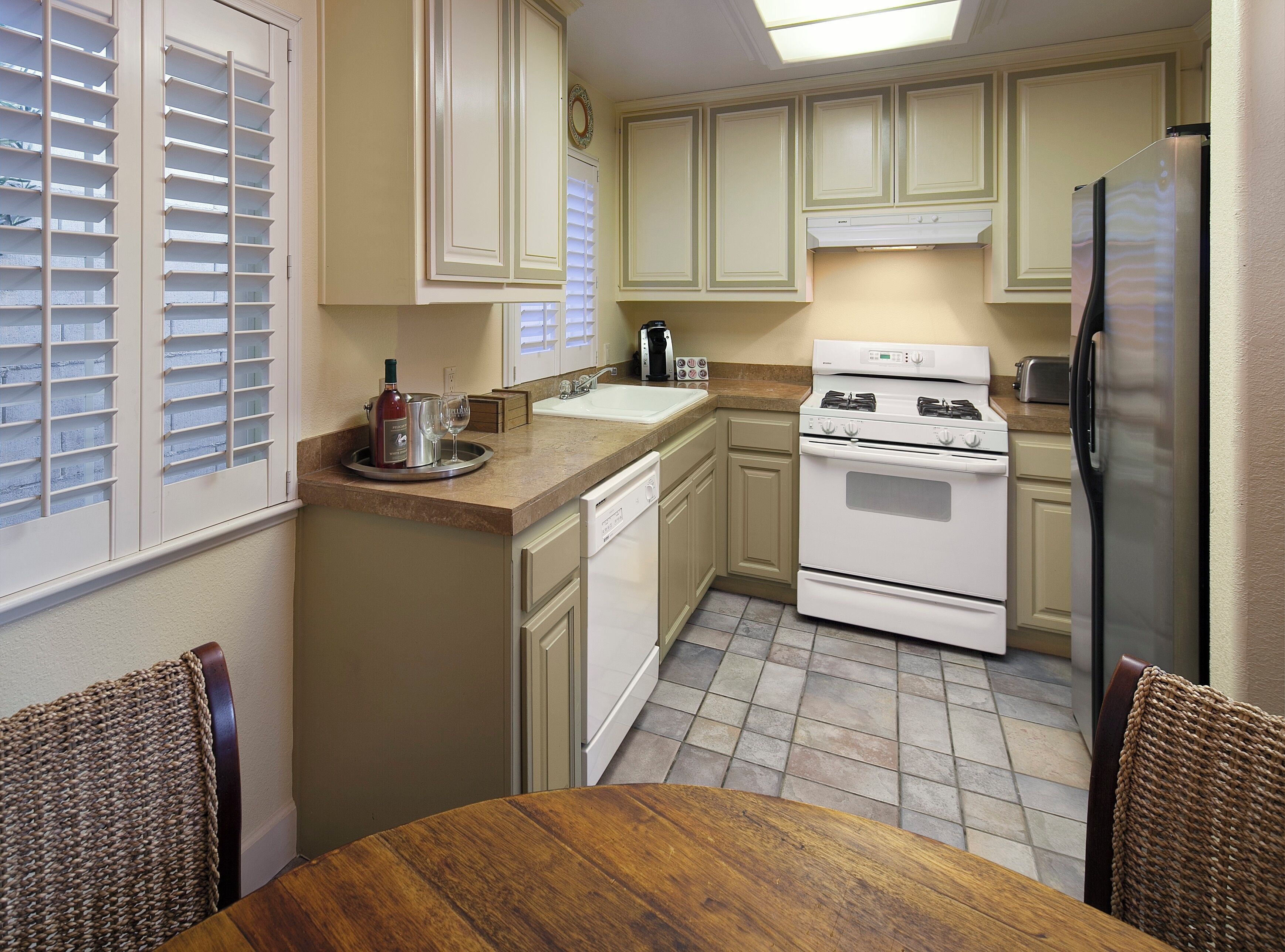 A kitchen with a dining table, cabinets, a refrigerator, and a stove.