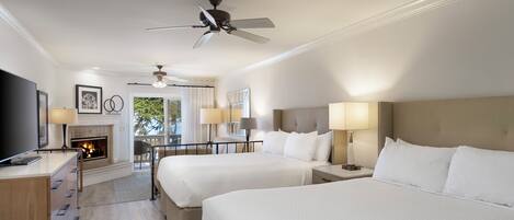 Quarto de hotel com duas camas, lareira, televisão e ventoinha no teto.
