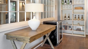 Une pièce avec une table en bois, une lampe et un meuble à vin contenant des bouteilles et des verres.