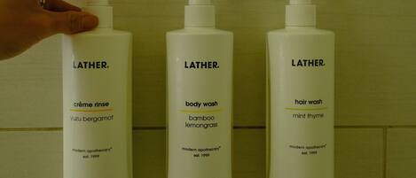 Drei Latherm Toilettenartikel-Flaschen vor einer gefliesten Wand.