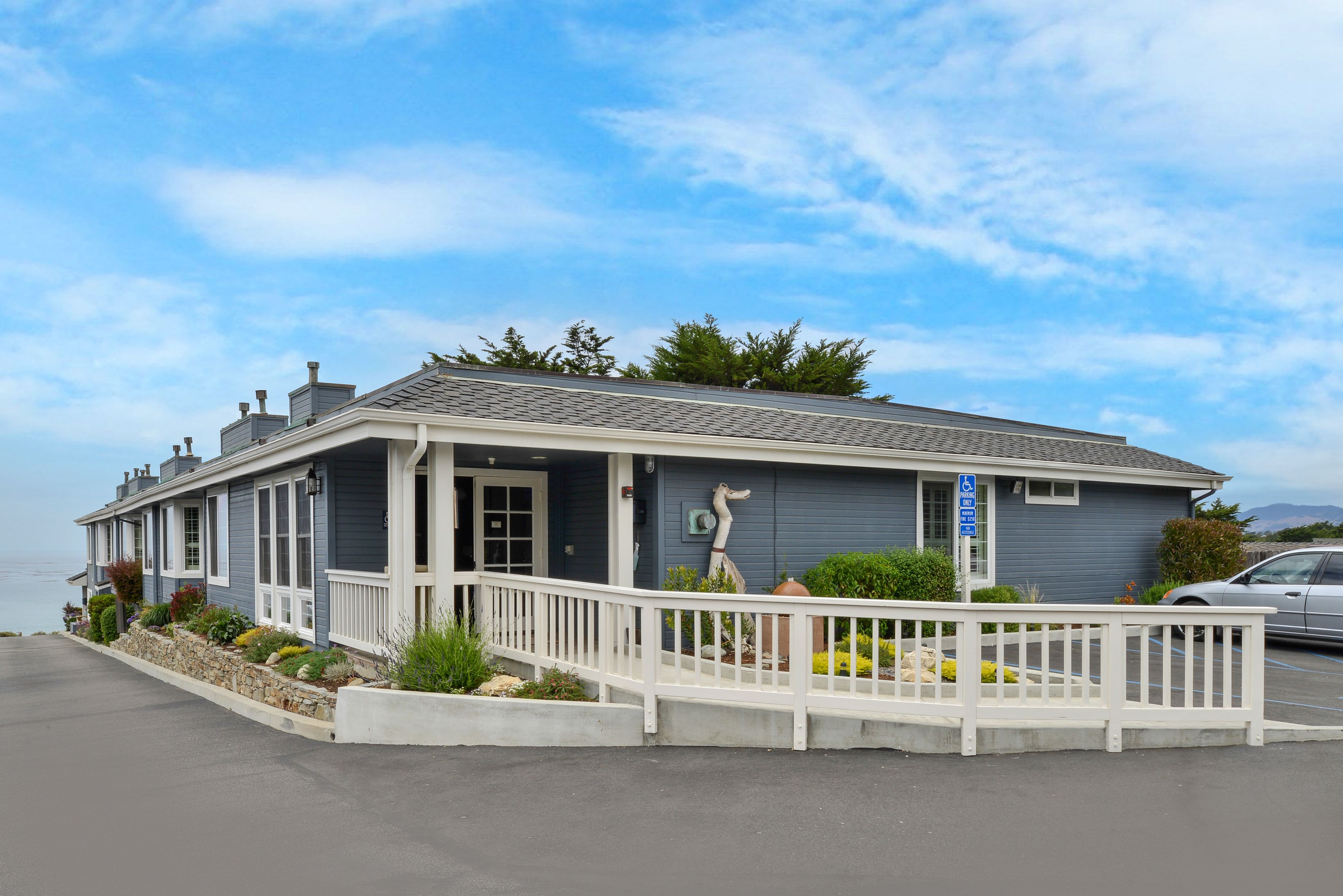 A coastal house with a porch, a wheelchair-accessible entrance, and a parking area.