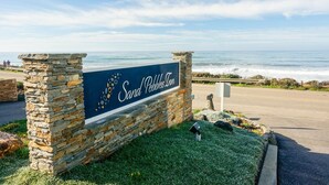 A sign for Sand Pebbles Inn with a view of the ocean. - Sand Pebbles Inn (Cambria)