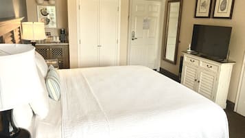 A neatly arranged hotel room with a large bed, a television, a dresser, and a mirror.