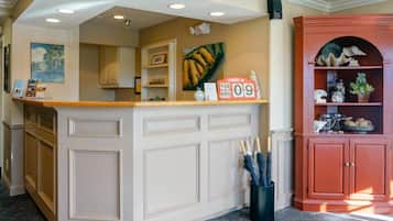 A reception area with a counter, a clock displaying the date, and a shelf with decorative items.