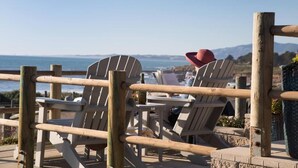 A wooden deck with Adirondack chairs overlooking a coastal view. - Sand Pebbles Inn (Cambria)