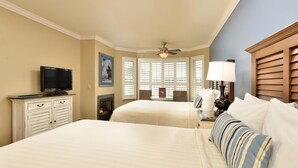 A hotel room with two beds, a television, a fireplace, and a window with shutters.