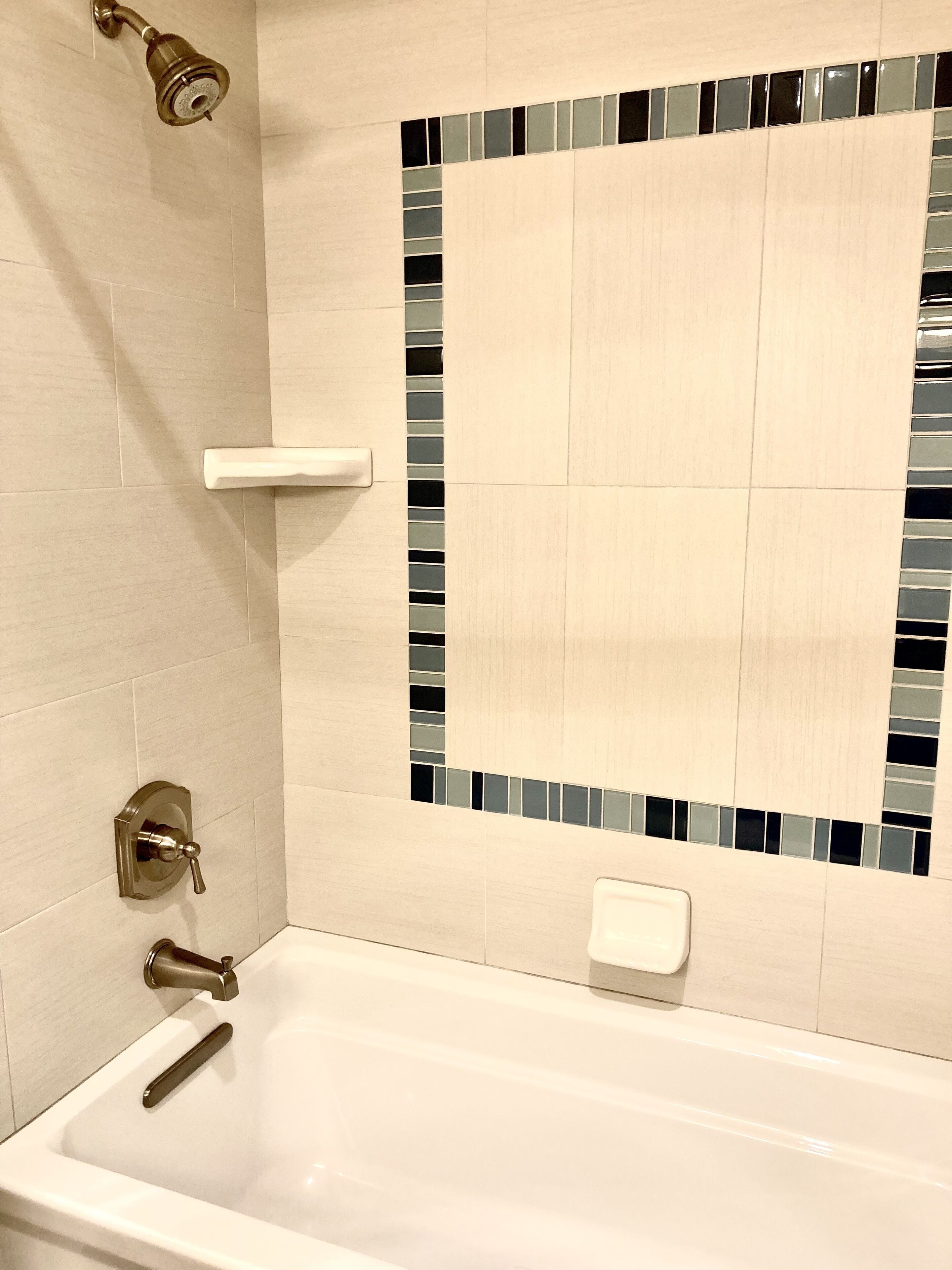 Un baño con bañera, cabezal de ducha y secador de manos.