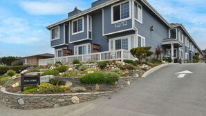 A two-story house with a 'WELCOME' sign in front, number 6252, and a landscaped garden with various plants and rocks. - Sand Pebbles Inn (Cambria)