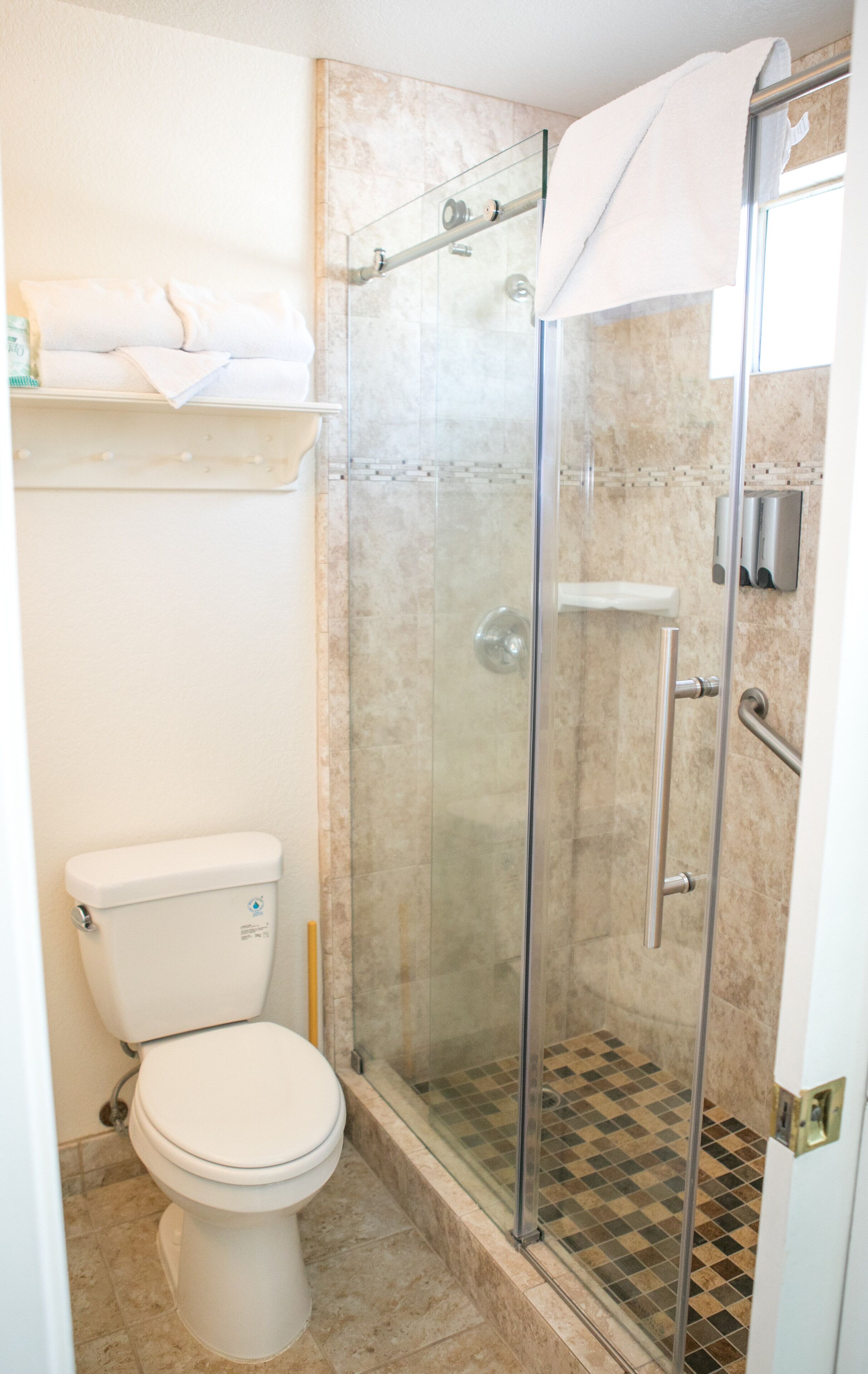Un baño con ducha de mampara de vidrio, inodoro y lavamanos.