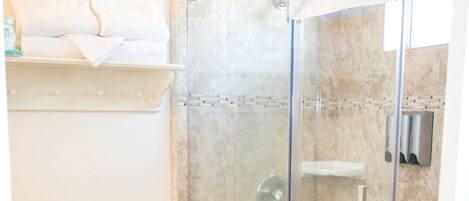 Un baño con ducha de mampara de vidrio, inodoro y lavamanos.