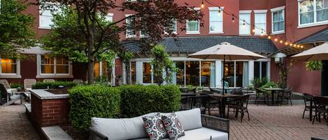 An outdoor patio area with a sofa, chairs, tables, and string lights.