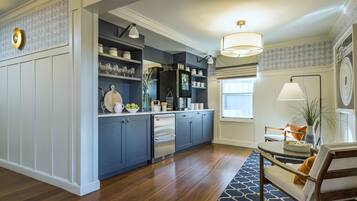 A modern kitchen with blue cabinets, stainless steel appliances, and a dining area with a wooden table and chairs.