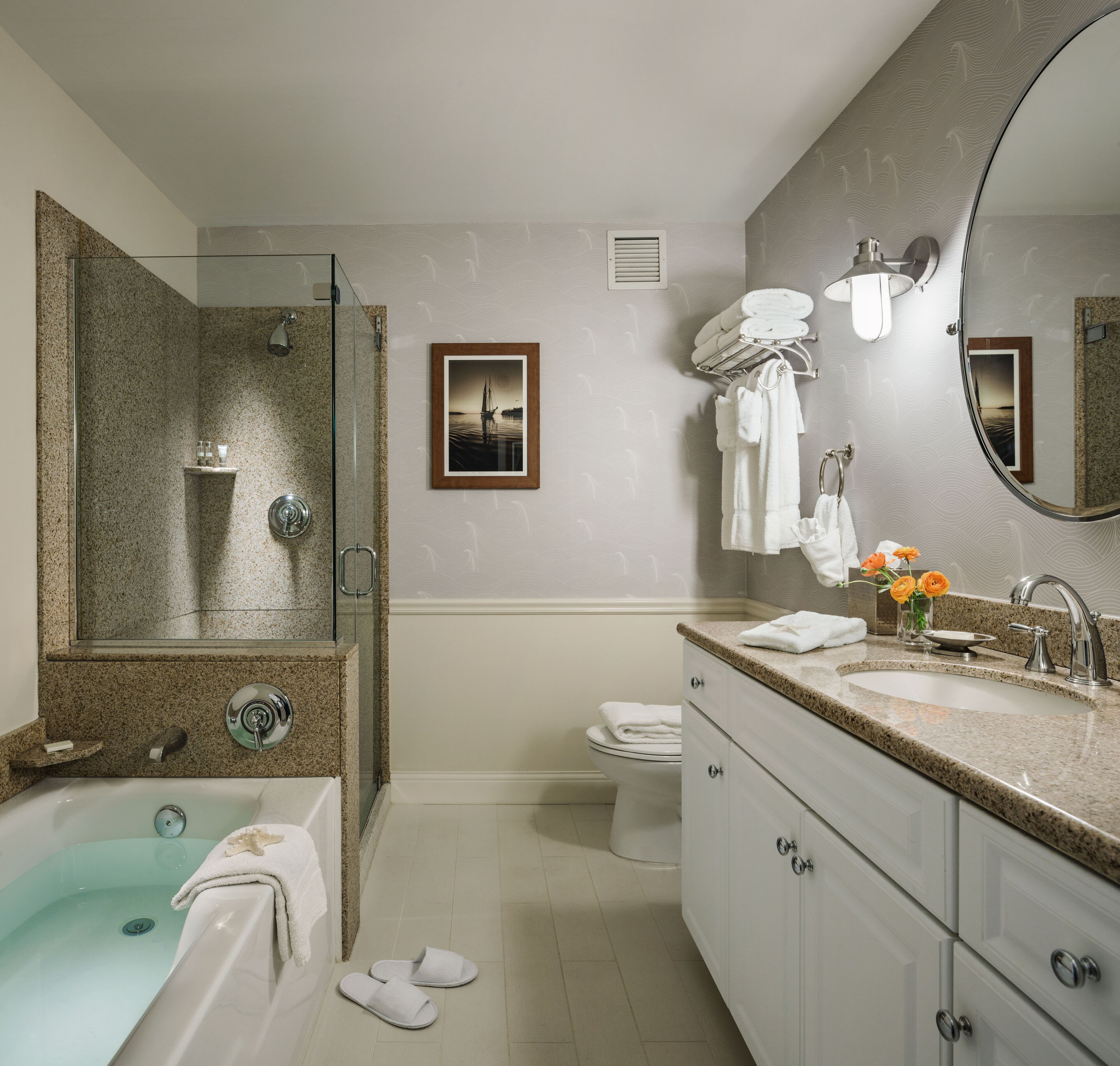 A modern bathroom with a glass-enclosed shower, a freestanding bathtub, a toilet, and a vanity with a sink and mirror.