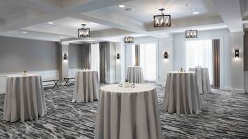 A conference room with round tables, recessed lighting, and a patterned carpet.