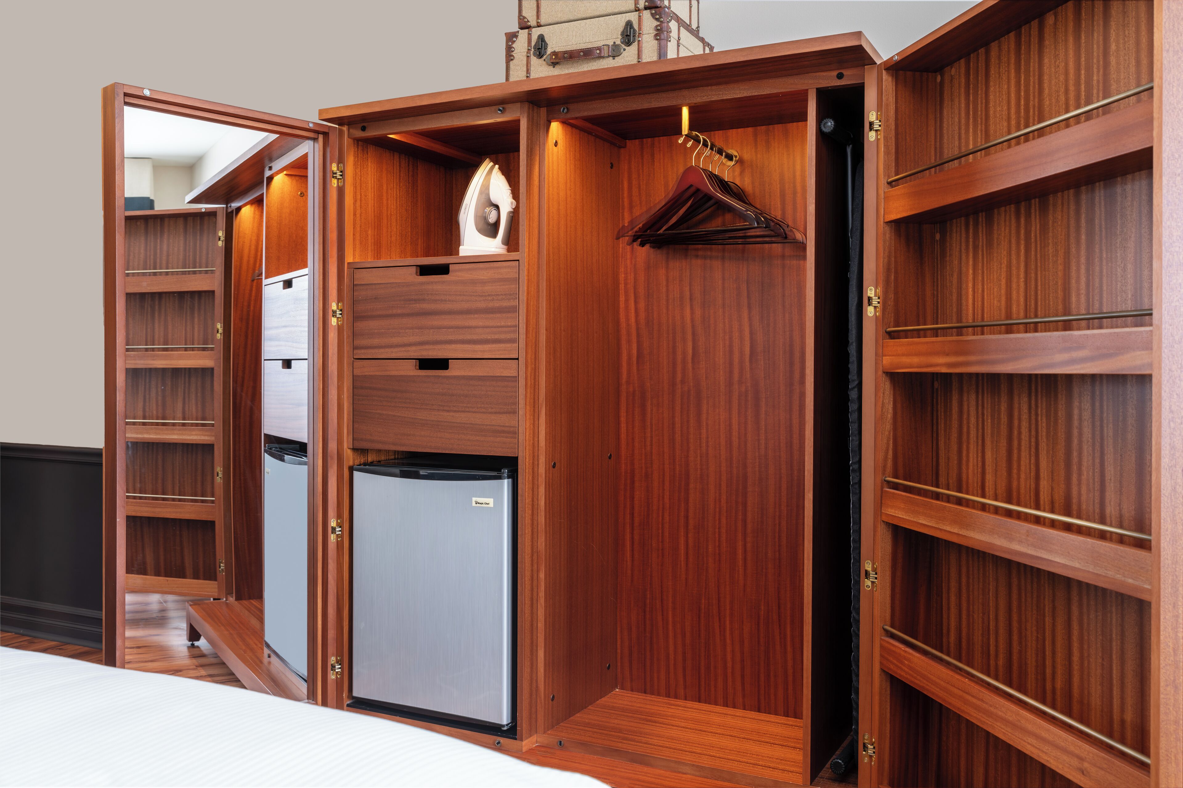 A compact wooden wardrobe with multiple shelves, a hanging rack, and a built-in mini-fridge.
