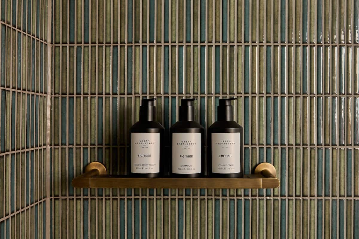 A shelf with three Urban Apothecary products: Fig Tree Hand & Body Wash, Shampoo, and Conditioner.