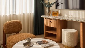 A modern hotel room with a round white table, a comfortable armchair, a wooden desk, and a large flat-screen TV. - Hotel Indigo London K West Shepherd's Bush by IHG (London)