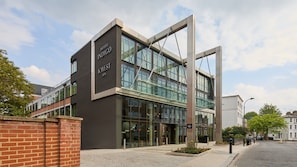 Un hotel moderno con fachada de vidrio, identificado como 'Hotel Indigo KWest Spa'.