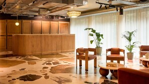 Un hall con mostrador de recepción, zona de estar y ventanas amplias.