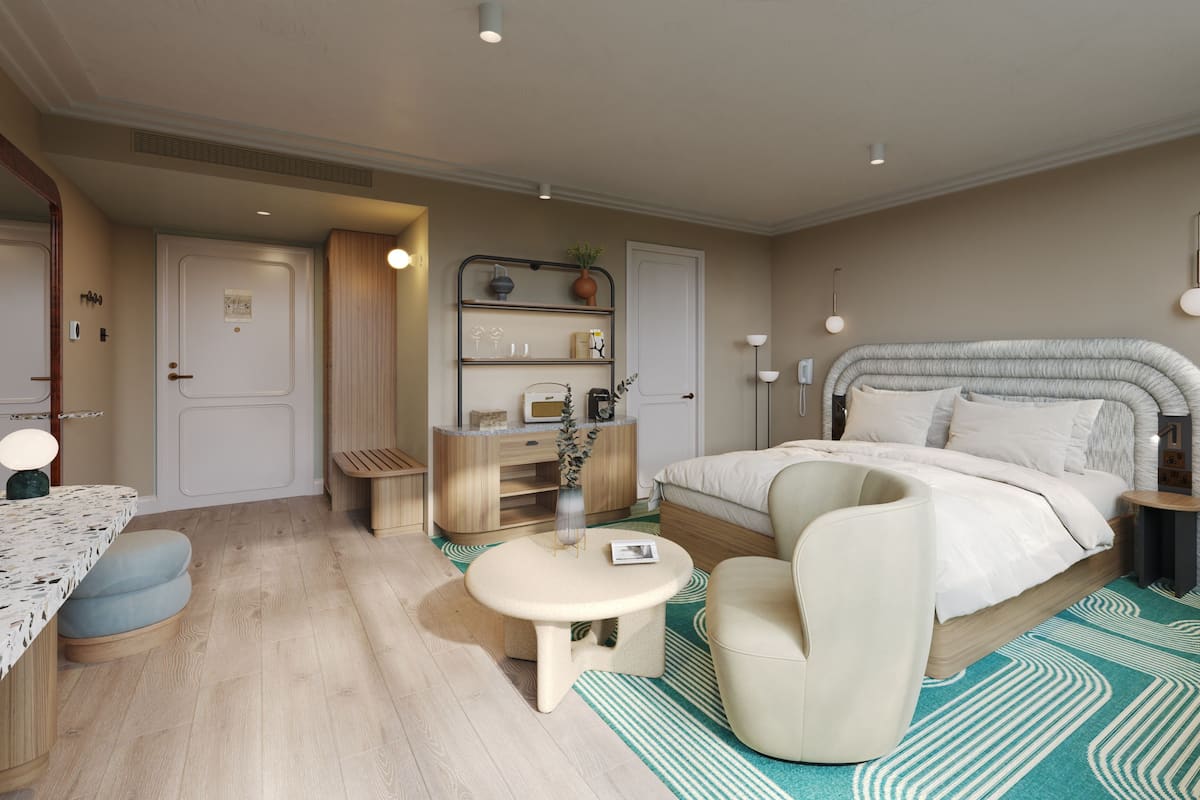 A modern bedroom with a bed, bedside table, chair, and a small desk with a lamp.