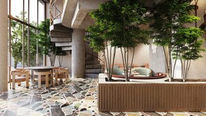A modern interior with a dining area, a staircase, and a seating area with cushions. - Hotel Indigo London K West Shepherd's Bush by IHG (London)