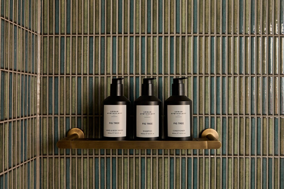 Un estante con tres productos de Urban Apothecary: jabón y limpiador corporal de Higo, champú y acondicionador.