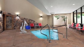 An indoor swimming pool area with stone walls, red and blue chairs, and a stone column. - Holiday Inn Express Hotel & Suites Marina - State Beach Area by IHG (Marina)