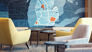 Un interior moderno con dos sillones amarillos, una mesita y una gran obra de arte abstracta en la pared.