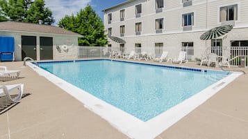 Una piscina al aire libre, sombrillas, sillones reclinables de piscina